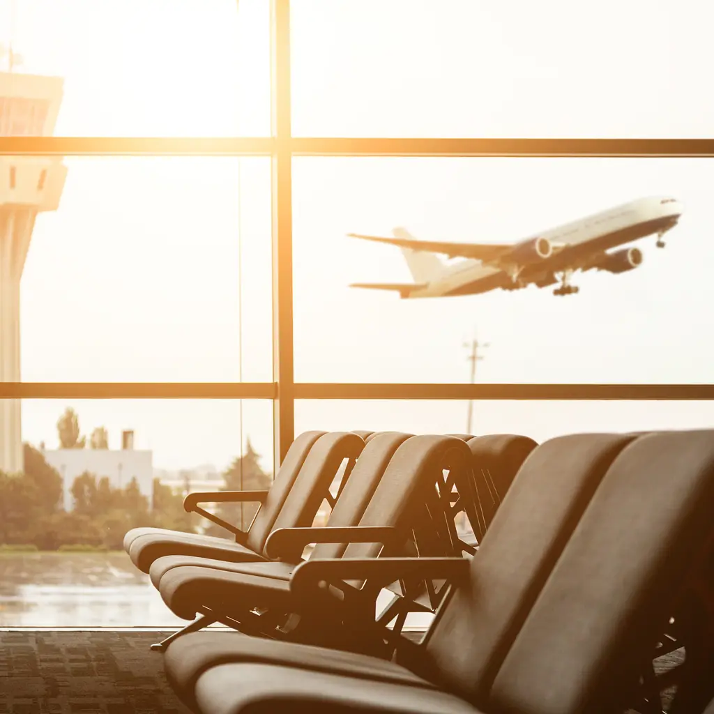 Rows of empty seats at a quiet airport gate beside a large window with an aircraft outside