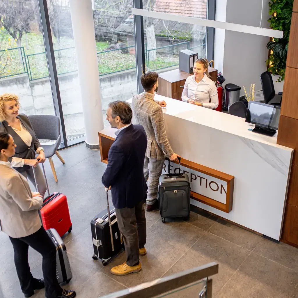 Travelers with roller bags at a hotel front desk late at night