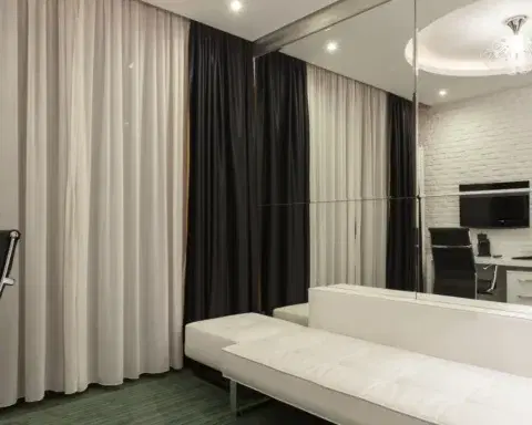 A modern city hotel room with striped curtains and a sofa, illustrating a standard to deluxe room upgrade.