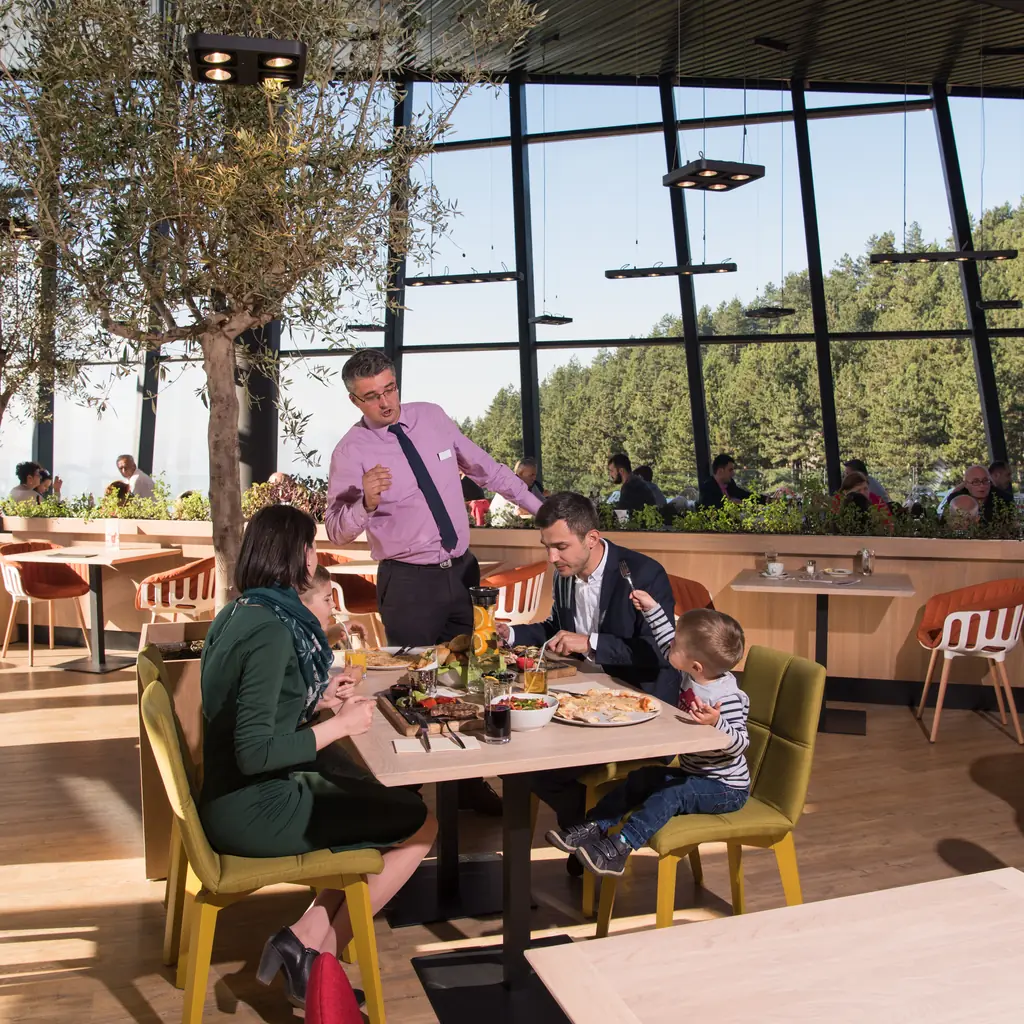 A family enjoying lunch together at a bright resort restaurant, illustrating dining variety across resort tiers.