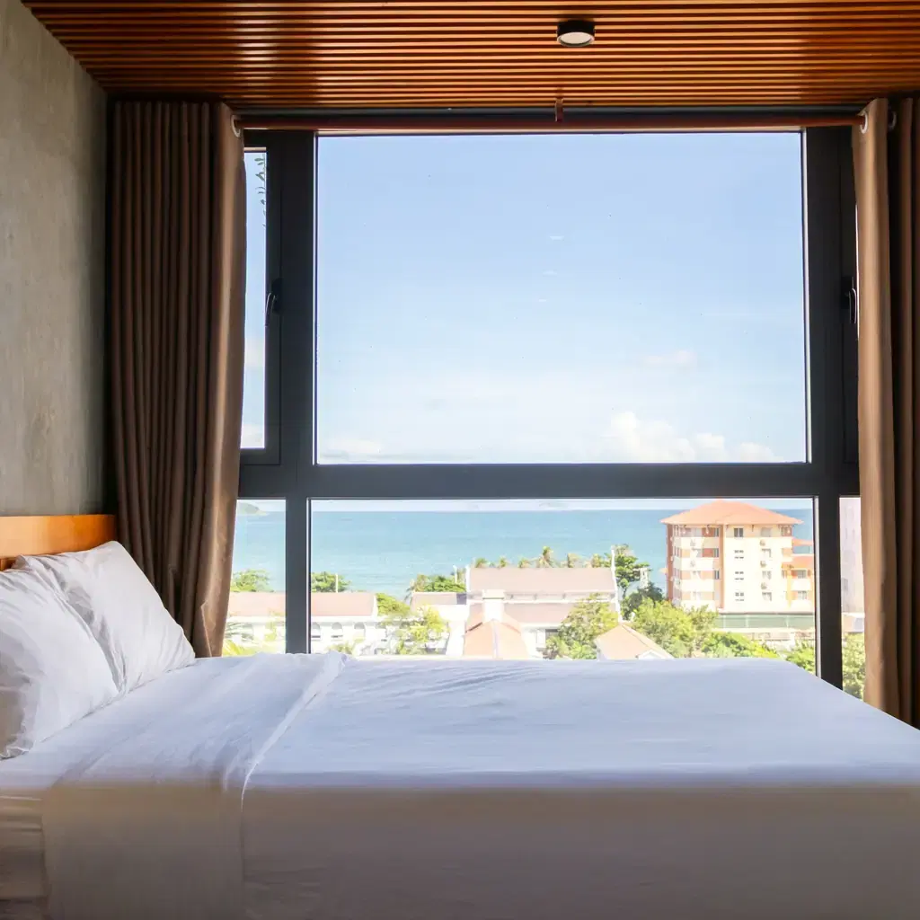 A minimalist bedroom with a window showing a partial, angled ocean view, illustrating an oceanview category.