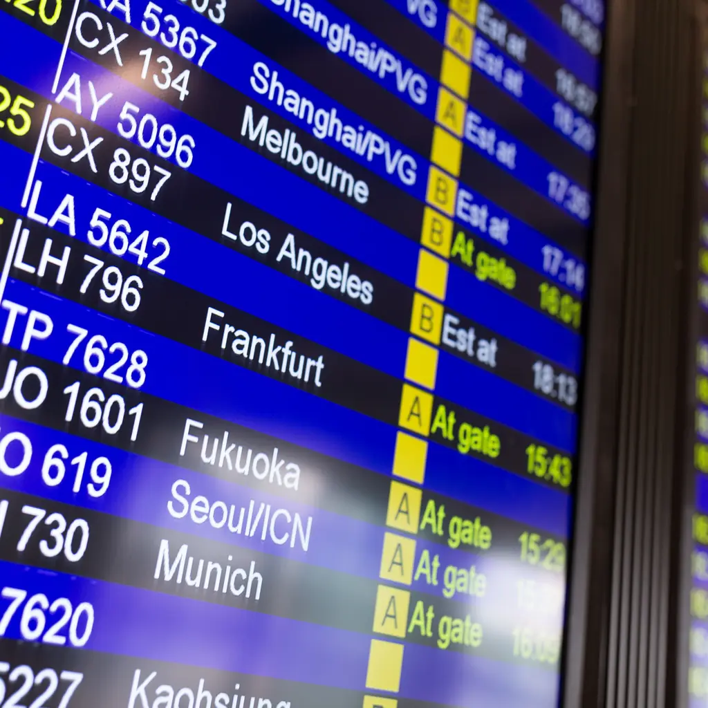 An airport departure board showing multiple flight numbers and destinations, illustrating how codeshares complicate which aircraft a traveler actually flies.