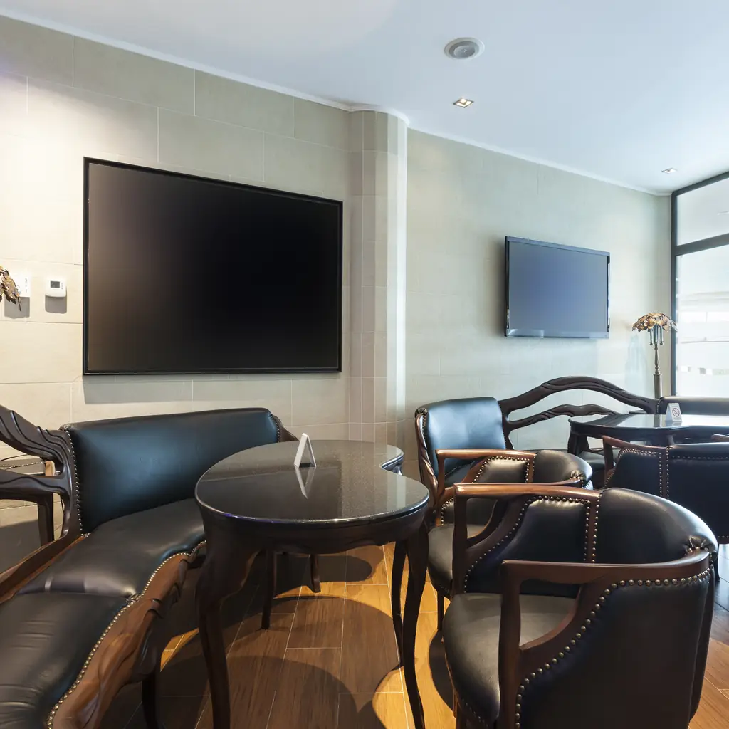 A luxury hotel lobby lounge with leather seating and a television, illustrating a club or executive lounge bundling several perks.