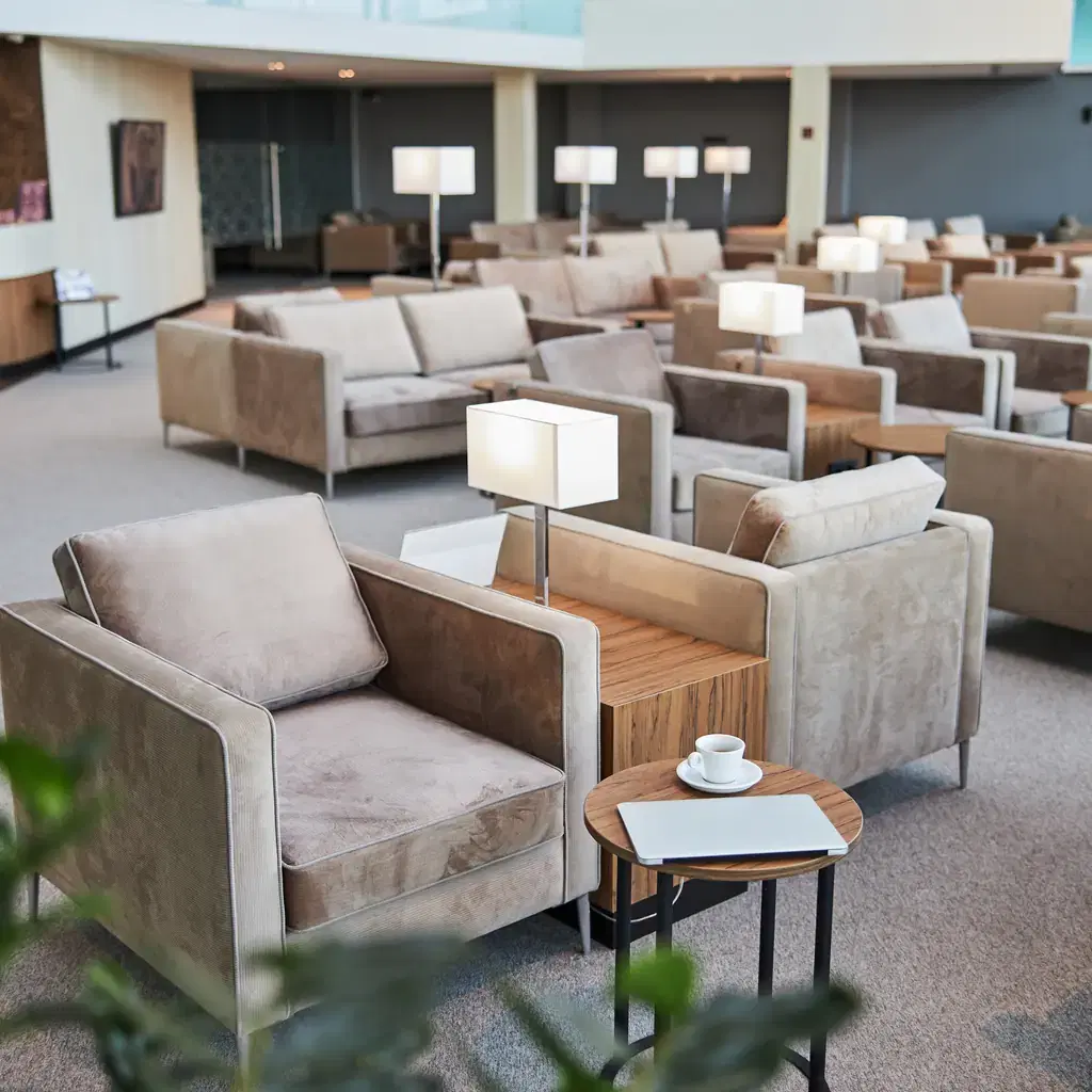 A spacious airport lounge interior with armchairs and soft lighting, illustrating a business-class ticket's included lounge access.