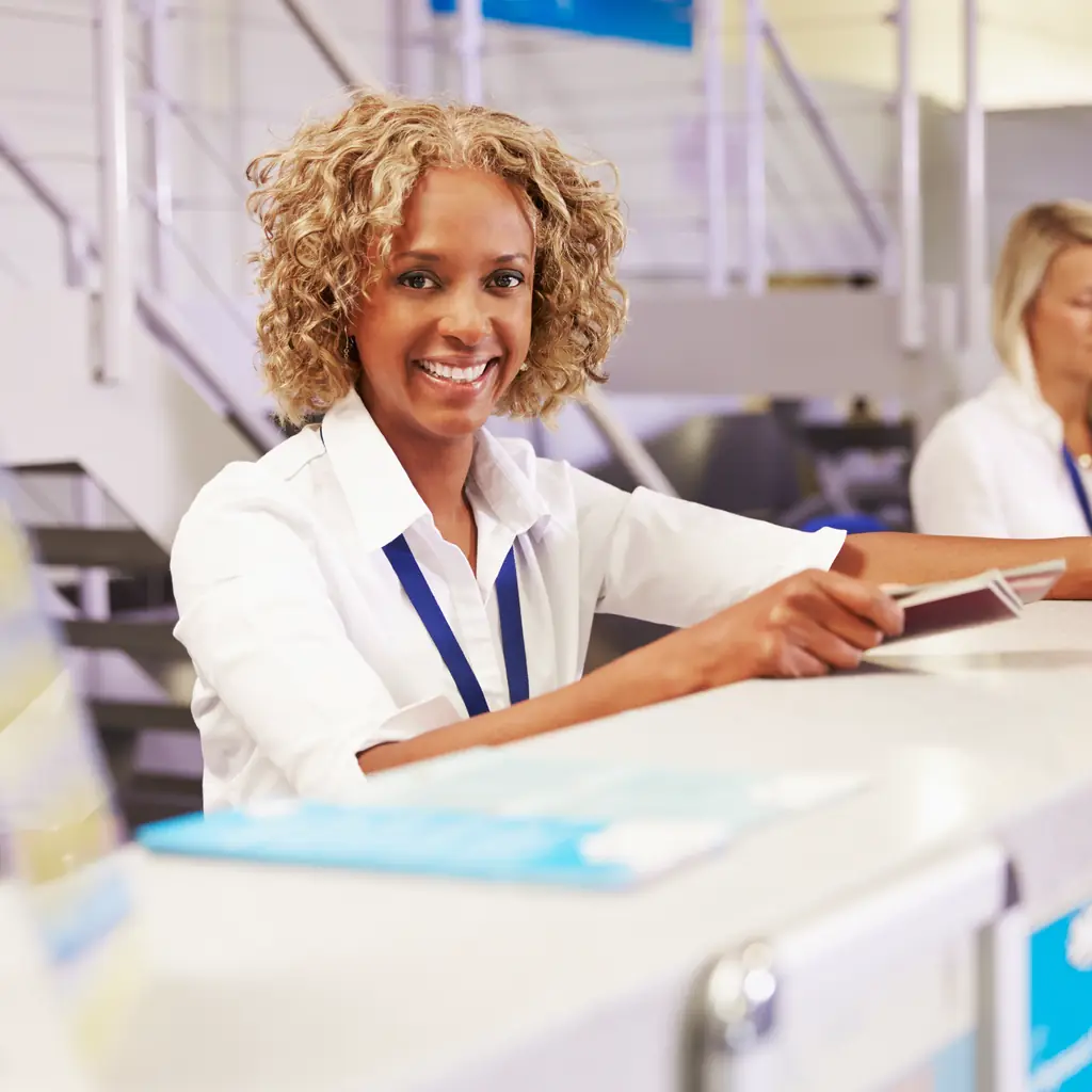Airline staff working at an airport check-in desk, illustrating how elite status can unlock lounge access even for economy passengers.