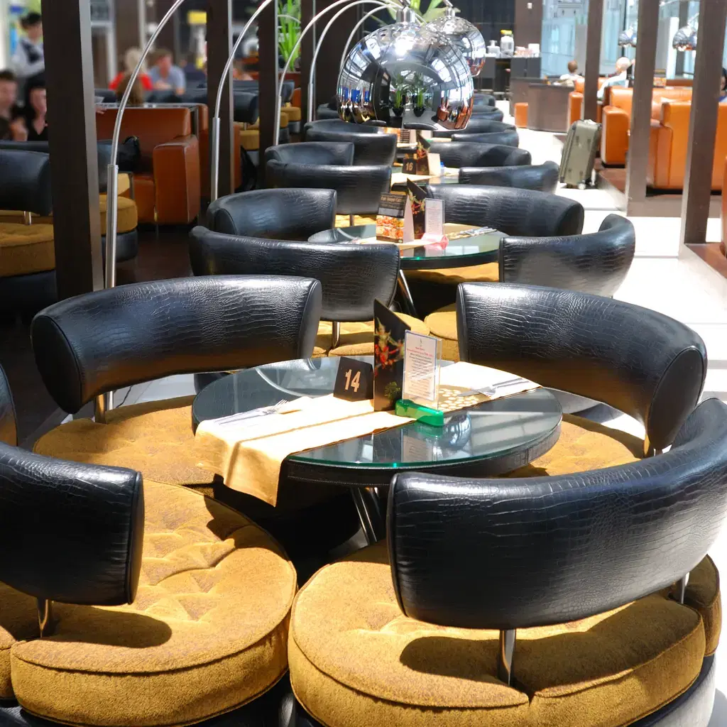 A modern airport lounge interior with lounge seating, illustrating a pay-per-visit lounge network that fills a different gap than airline-branded lounges.