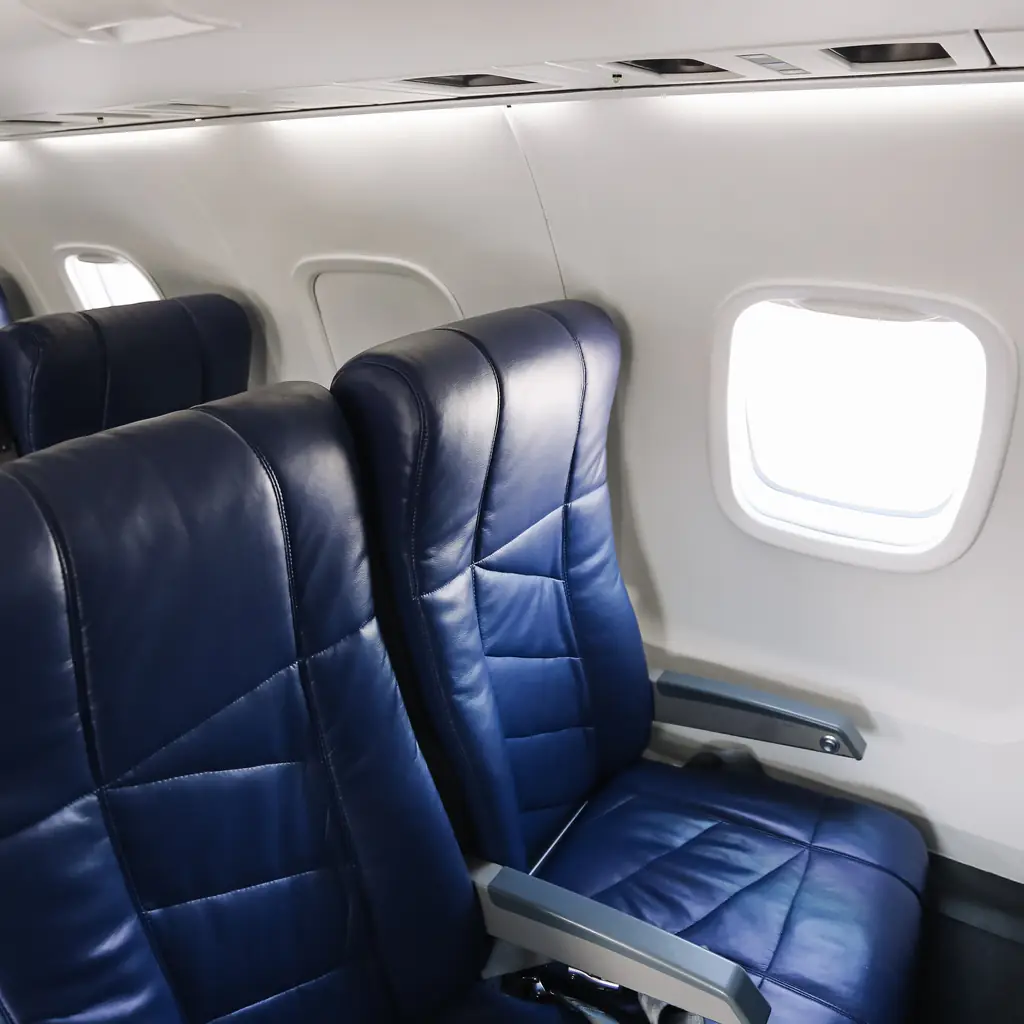 An empty airplane cabin interior with blue leather seats, the kind of cabin where a premium-economy upgrade changes the seat itself.