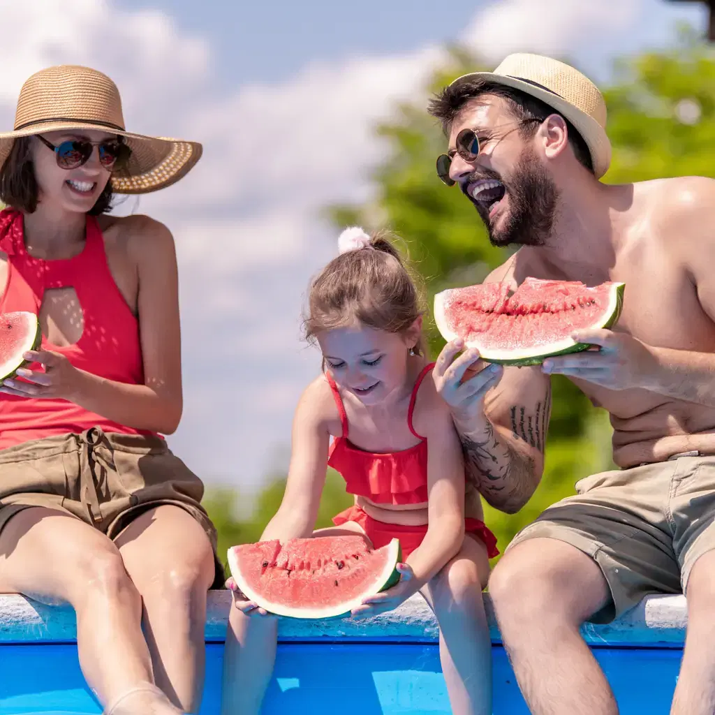 A family relaxing poolside together, illustrating a realistic travel day compared across resort tiers.