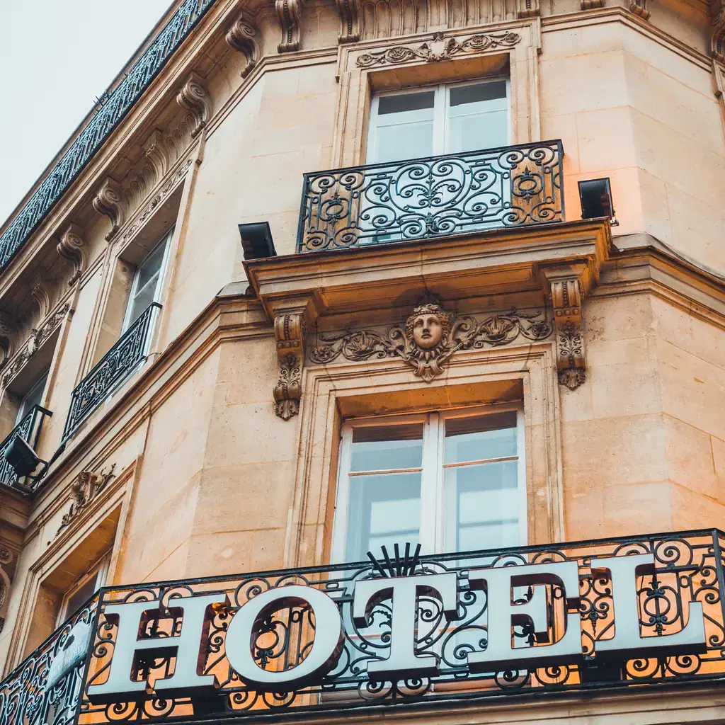 The ornate facade of a European hotel with a hanging hotel sign, illustrating hotel location tier as a separate upgrade from star rating.
