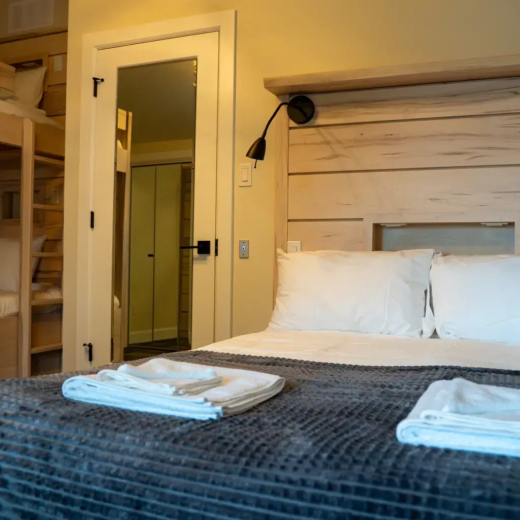 A small hotel room with a double bed and bunk bed, illustrating a family-friendly room configuration.