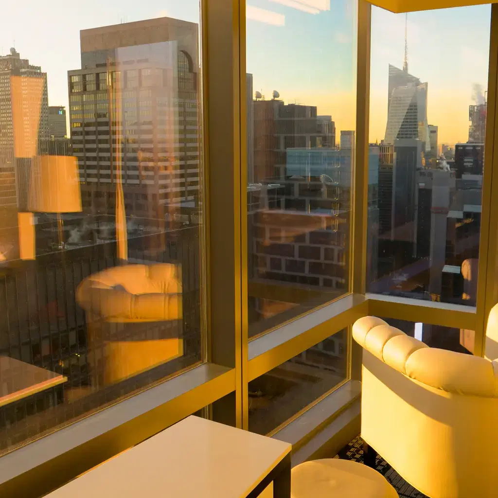 A city skyline view at sunrise from inside a hotel room, illustrating a priced view category.
