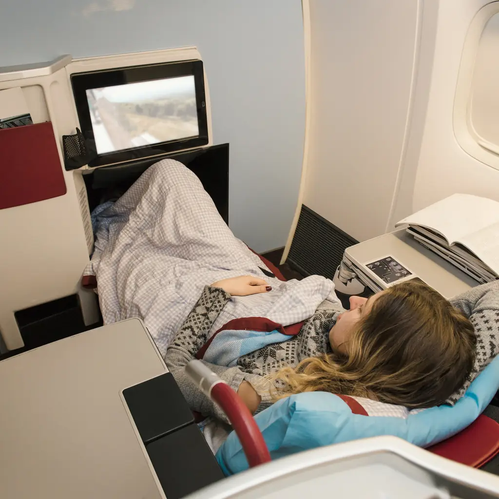 A passenger lying fully flat in a business class seat, illustrating the real jump long-haul business class makes over domestic first class.