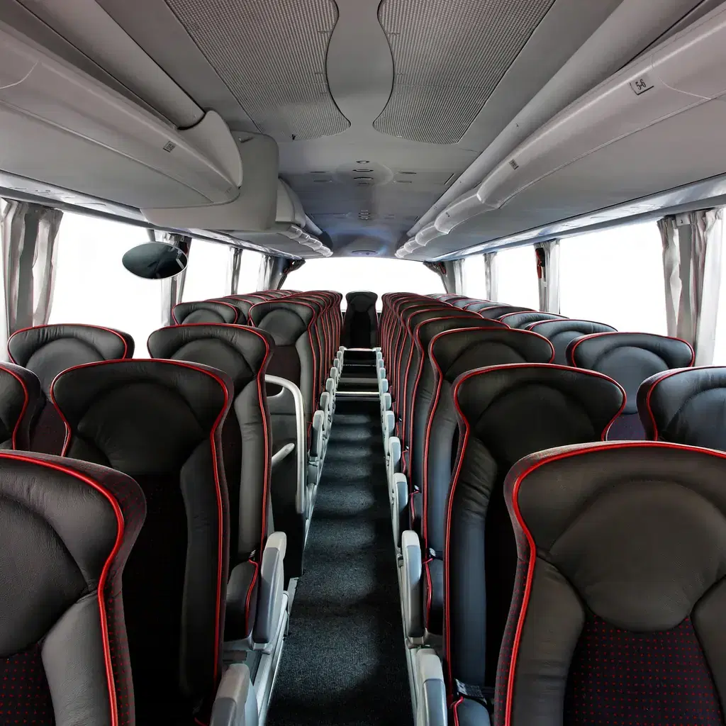 The interior of a large tour coach bus with red-trimmed leather seats, illustrating the coach itself as a line-item upgrade.