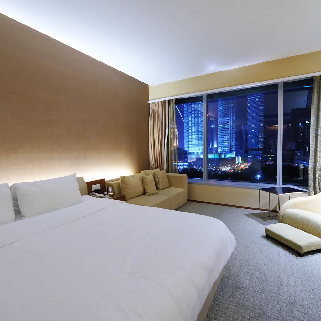 A luxurious hotel room with a large window overlooking a lit-up city skyline, illustrating a formalized corner room category.