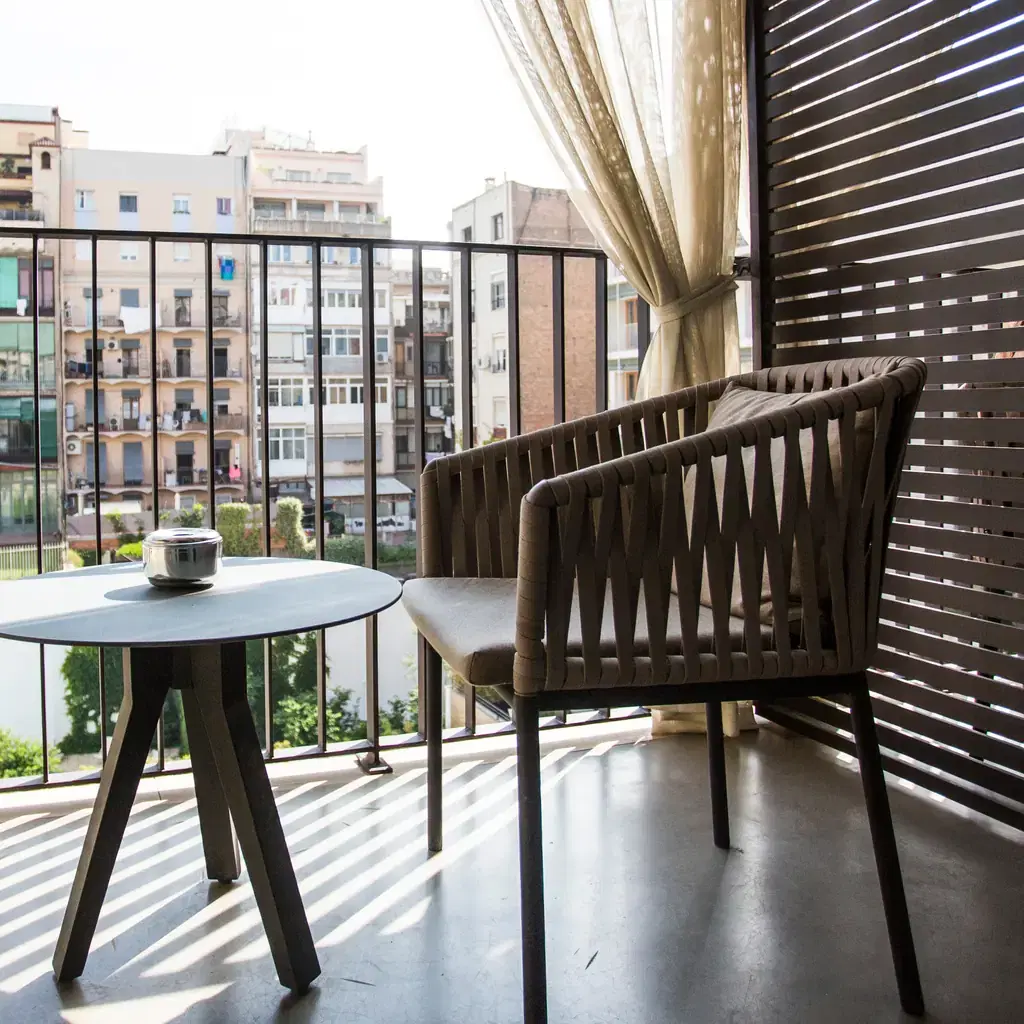 A small table and chair on a city hotel balcony overlooking an urban courtyard, illustrating a balcony or terrace room.