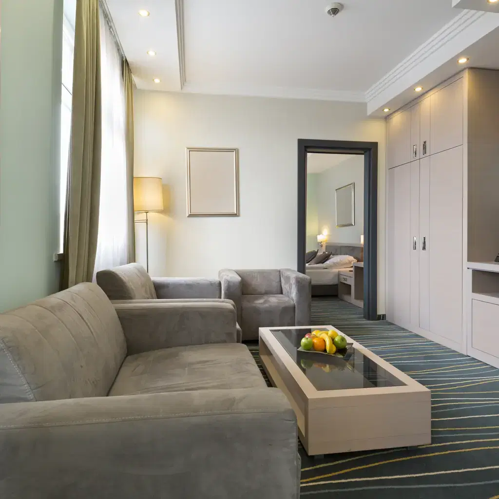 A hotel suite interior showing a separate living room area with a sofa, illustrating the difference between a junior suite and a full suite.