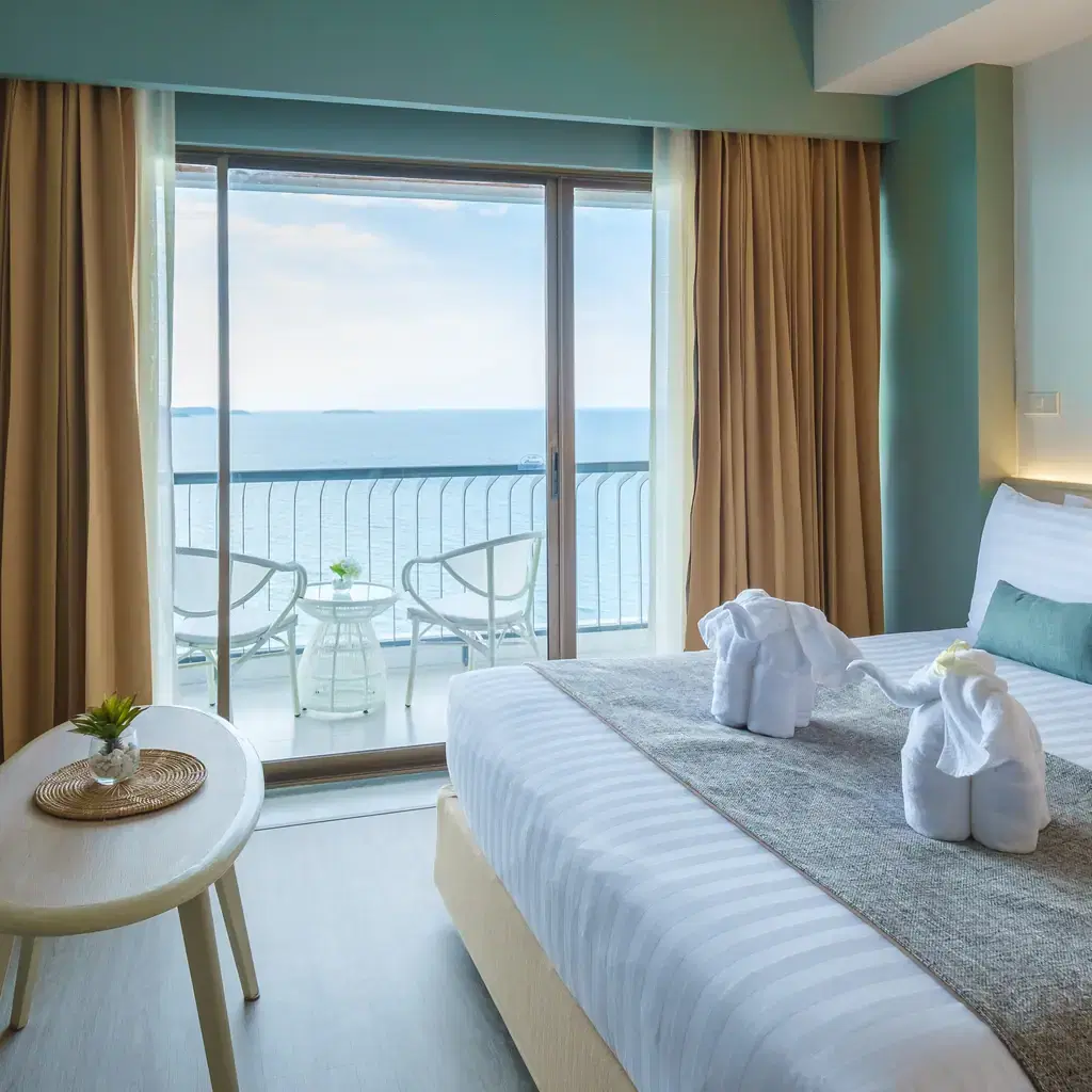 A bright hotel room with a full ocean view from the bed, illustrating an oceanfront-style room category distinct from beachfront.